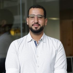 Moustafa Ramadan Man standing in from of a glass fronted office --ar 3:2 --v 7 Job ID: 2fcfa067-9edb-46fb-ade6-c6561ea509ba